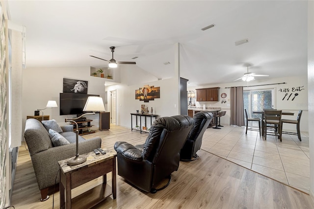 living room with ceiling fan, light hardwood / wood-style flooring, and vaulted ceiling