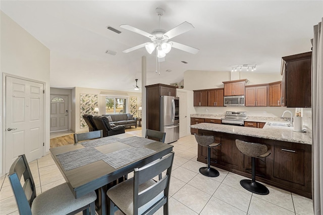 dining area featuring ceiling fan, light tile patterned flooring, sink, and vaulted ceiling