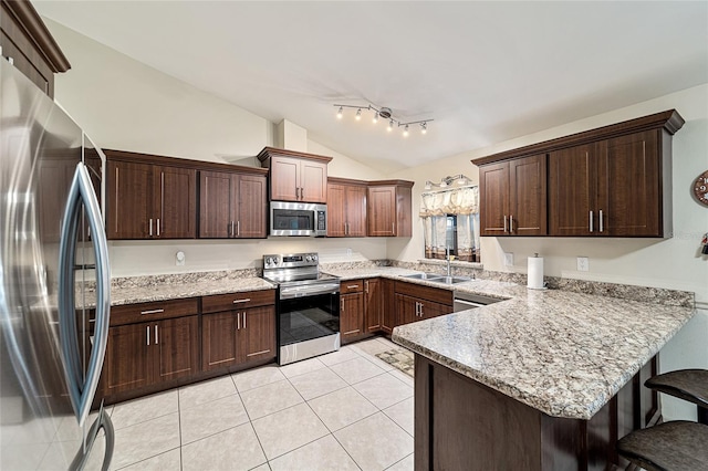 kitchen featuring light tile patterned floors, kitchen peninsula, appliances with stainless steel finishes, vaulted ceiling, and sink