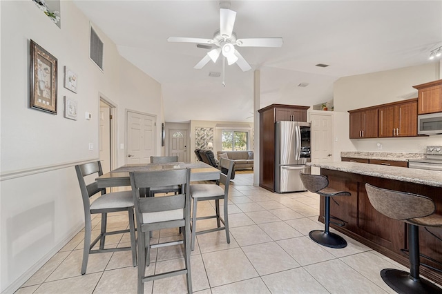 dining space with lofted ceiling, light tile patterned floors, and ceiling fan