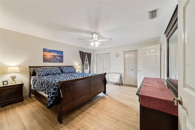 bedroom featuring ceiling fan, light wood-type flooring, and two closets