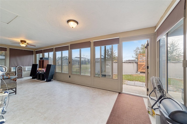 sunroom with ceiling fan and a water view