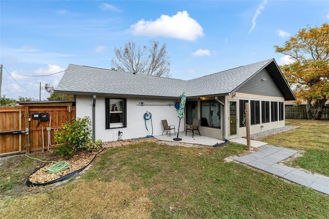 back of property featuring a lawn, a patio, and a sunroom