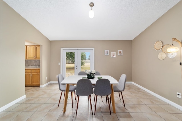 dining space with a textured ceiling, light tile patterned floors, lofted ceiling, and french doors