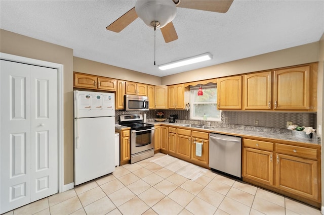 kitchen featuring sink, a textured ceiling, stainless steel appliances, and light tile patterned flooring