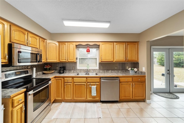 kitchen with decorative backsplash, appliances with stainless steel finishes, light tile patterned flooring, and a textured ceiling