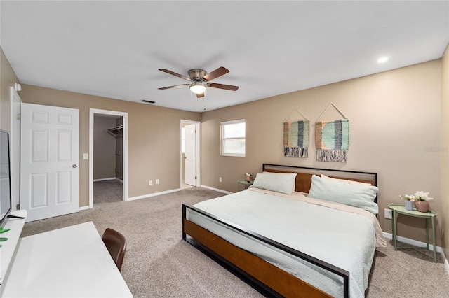 carpeted bedroom with ceiling fan, a closet, and a walk in closet