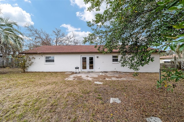 back of property featuring a lawn and french doors