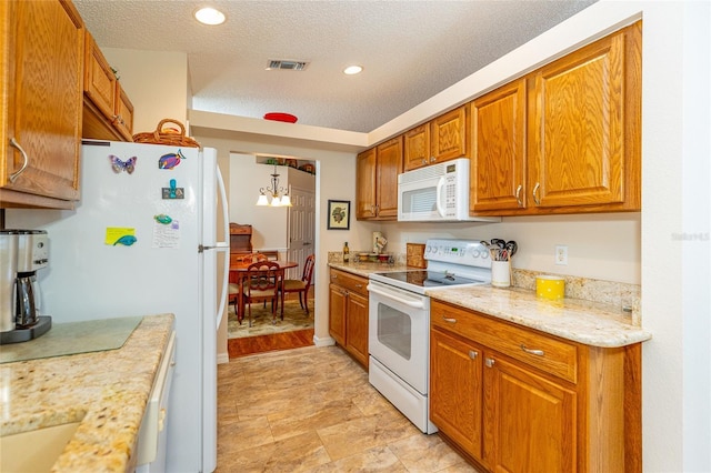 kitchen with hanging light fixtures, light stone counters, a chandelier, a textured ceiling, and white appliances