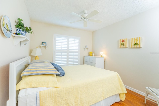 bedroom with ceiling fan, hardwood / wood-style floors, and a textured ceiling