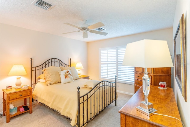 bedroom with ceiling fan, light colored carpet, and a textured ceiling