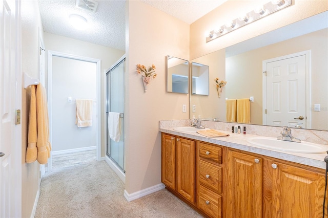 bathroom featuring vanity, a shower with shower door, and a textured ceiling