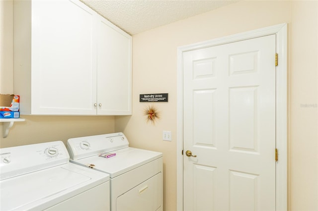 washroom with cabinets, a textured ceiling, and washing machine and dryer