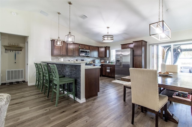 kitchen with appliances with stainless steel finishes, dark brown cabinets, and pendant lighting