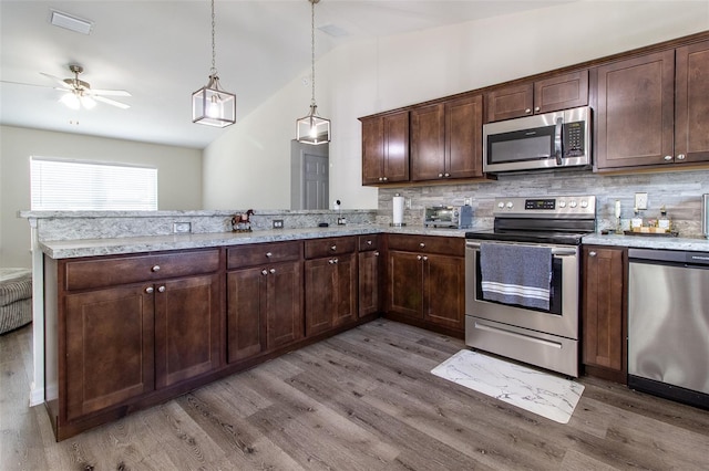 kitchen with stainless steel appliances, kitchen peninsula, pendant lighting, decorative backsplash, and dark brown cabinets