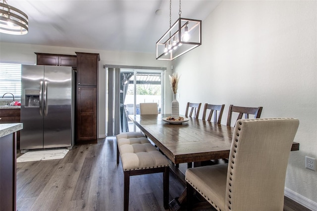 dining area featuring sink, dark hardwood / wood-style floors, and an inviting chandelier