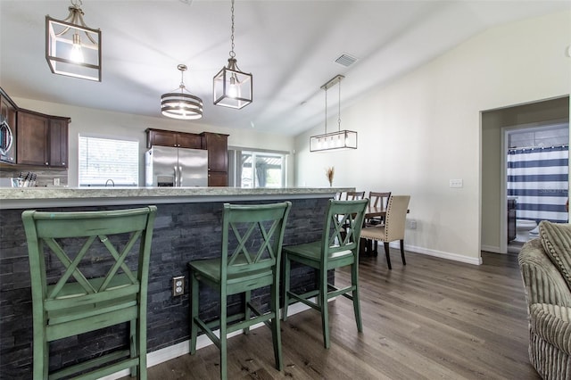 kitchen with dark brown cabinets, stainless steel fridge, hanging light fixtures, and vaulted ceiling