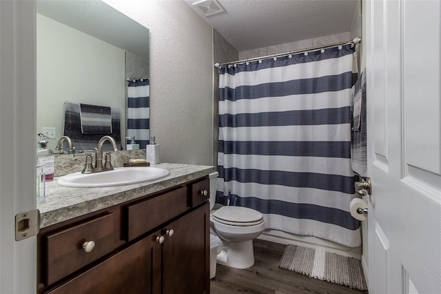 bathroom with vanity, toilet, wood-type flooring, and a textured ceiling