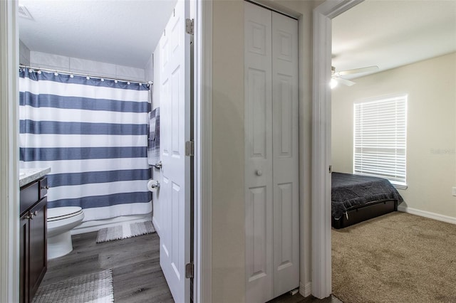 bathroom featuring vanity, hardwood / wood-style flooring, ceiling fan, toilet, and curtained shower