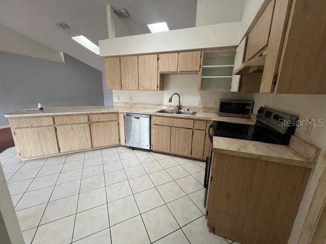 kitchen featuring appliances with stainless steel finishes, light brown cabinetry, vaulted ceiling, sink, and light tile patterned floors