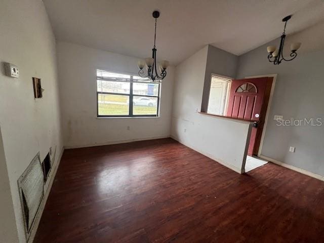 unfurnished dining area featuring dark hardwood / wood-style floors, vaulted ceiling, and an inviting chandelier