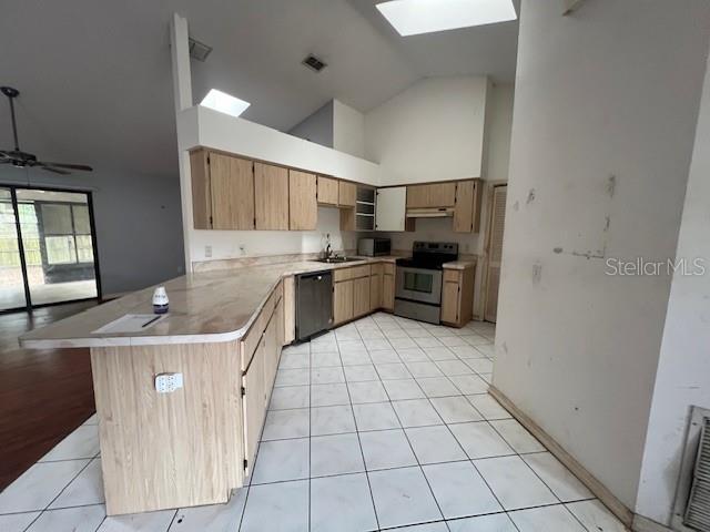 kitchen with a skylight, stainless steel electric range oven, black dishwasher, light brown cabinetry, and kitchen peninsula