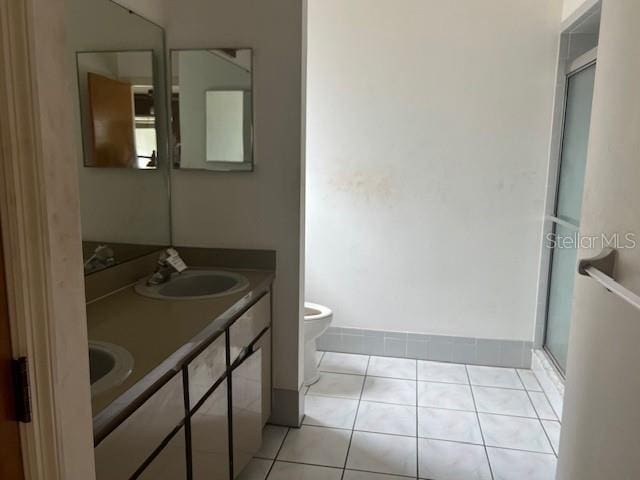 bathroom with tile patterned flooring, vanity, a shower with shower door, and toilet