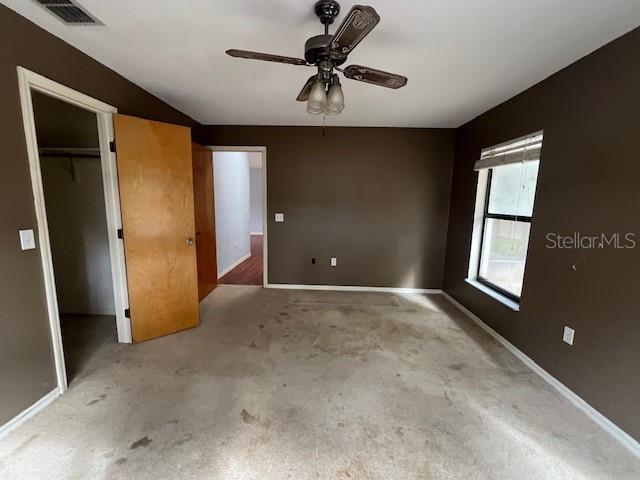 unfurnished bedroom with a walk in closet, ceiling fan, and a closet