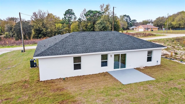 back of property with a patio area, a shingled roof, a lawn, and stucco siding