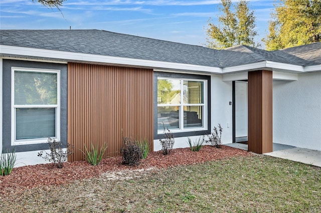 view of side of home with a shingled roof and a yard