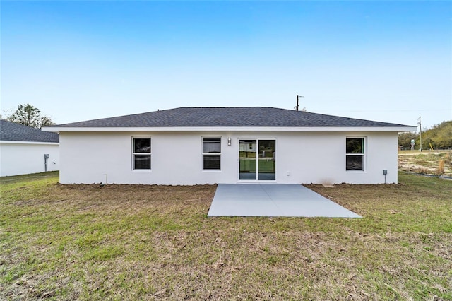 rear view of house with a patio area, roof with shingles, stucco siding, and a yard