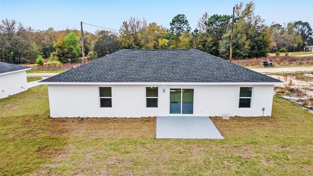 back of property featuring stucco siding, roof with shingles, a yard, and a patio