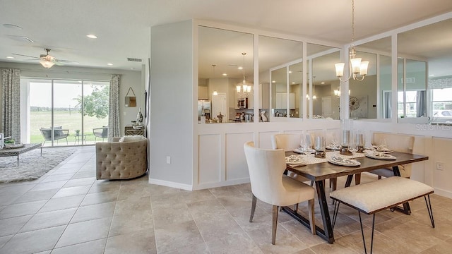 tiled dining room featuring ceiling fan with notable chandelier