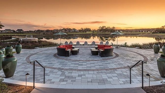 patio terrace at dusk featuring a water view