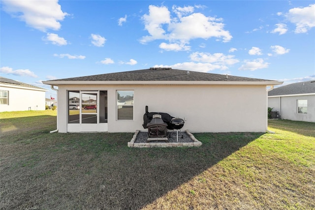 rear view of house with a lawn and a fire pit