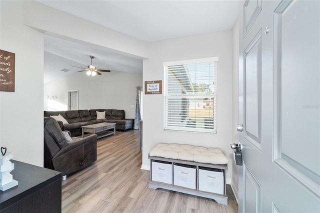 living room featuring ceiling fan, light wood-type flooring, and vaulted ceiling