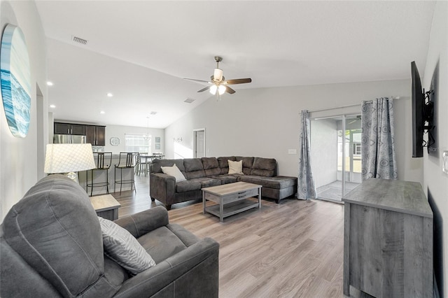 living room with ceiling fan, light wood-type flooring, and vaulted ceiling