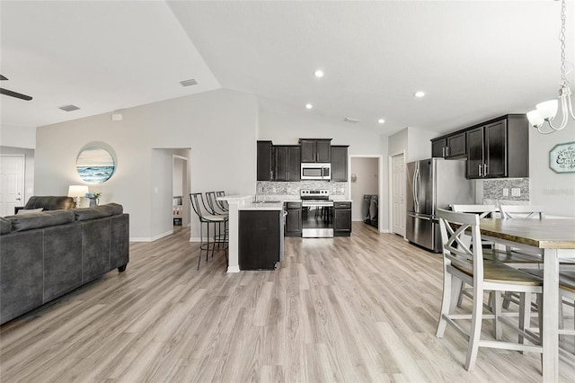 kitchen featuring appliances with stainless steel finishes, a center island, tasteful backsplash, a kitchen breakfast bar, and vaulted ceiling