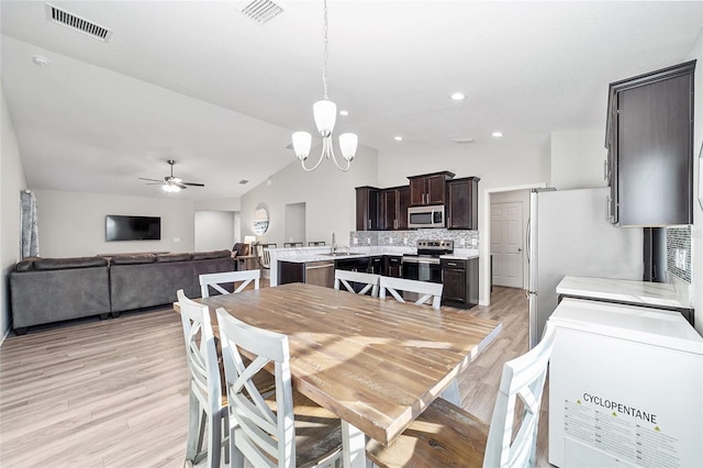 dining area with vaulted ceiling, ceiling fan with notable chandelier, light hardwood / wood-style flooring, and sink