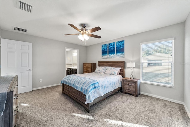 bedroom with ceiling fan, light carpet, and connected bathroom