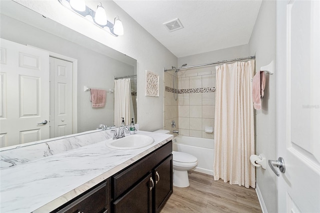 full bathroom with a textured ceiling, vanity, shower / bath combo with shower curtain, toilet, and hardwood / wood-style flooring