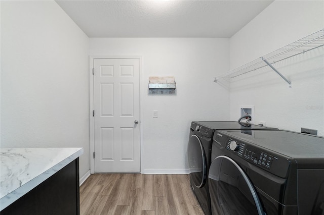 washroom featuring a textured ceiling, washer and clothes dryer, and light wood-type flooring