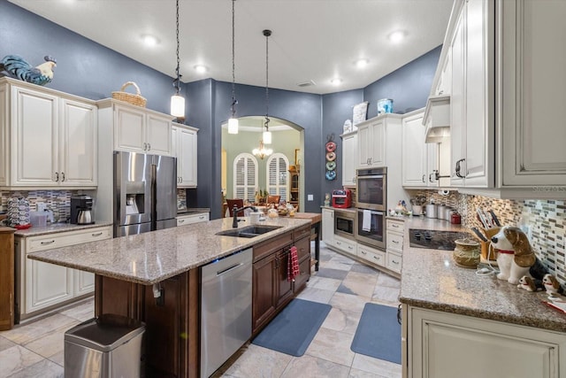 kitchen featuring sink, tasteful backsplash, a notable chandelier, an island with sink, and appliances with stainless steel finishes