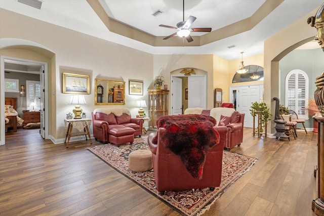 living room featuring wood-type flooring, a raised ceiling, and ceiling fan