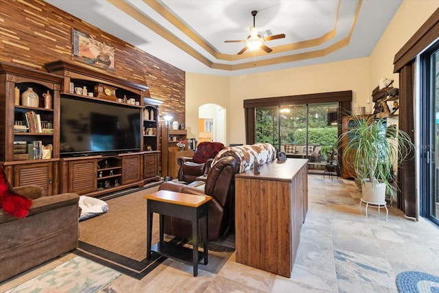 living room with a tray ceiling and ceiling fan