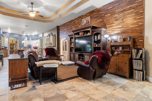 living room with a raised ceiling and ceiling fan