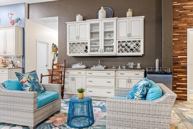 interior space with white cabinets, wood walls, and backsplash