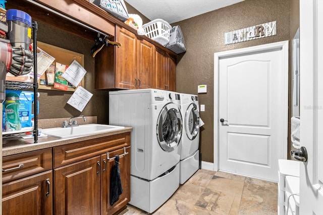 clothes washing area featuring a textured ceiling, cabinets, separate washer and dryer, and sink