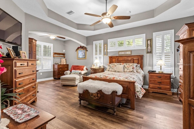 bedroom featuring a tray ceiling, ceiling fan, and dark hardwood / wood-style floors