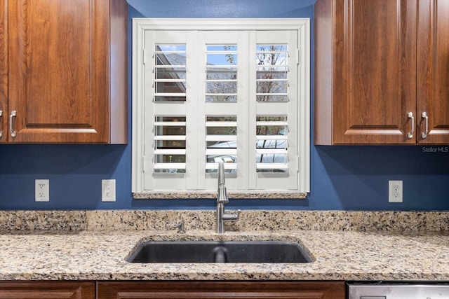 kitchen featuring dishwasher, sink, and light stone counters